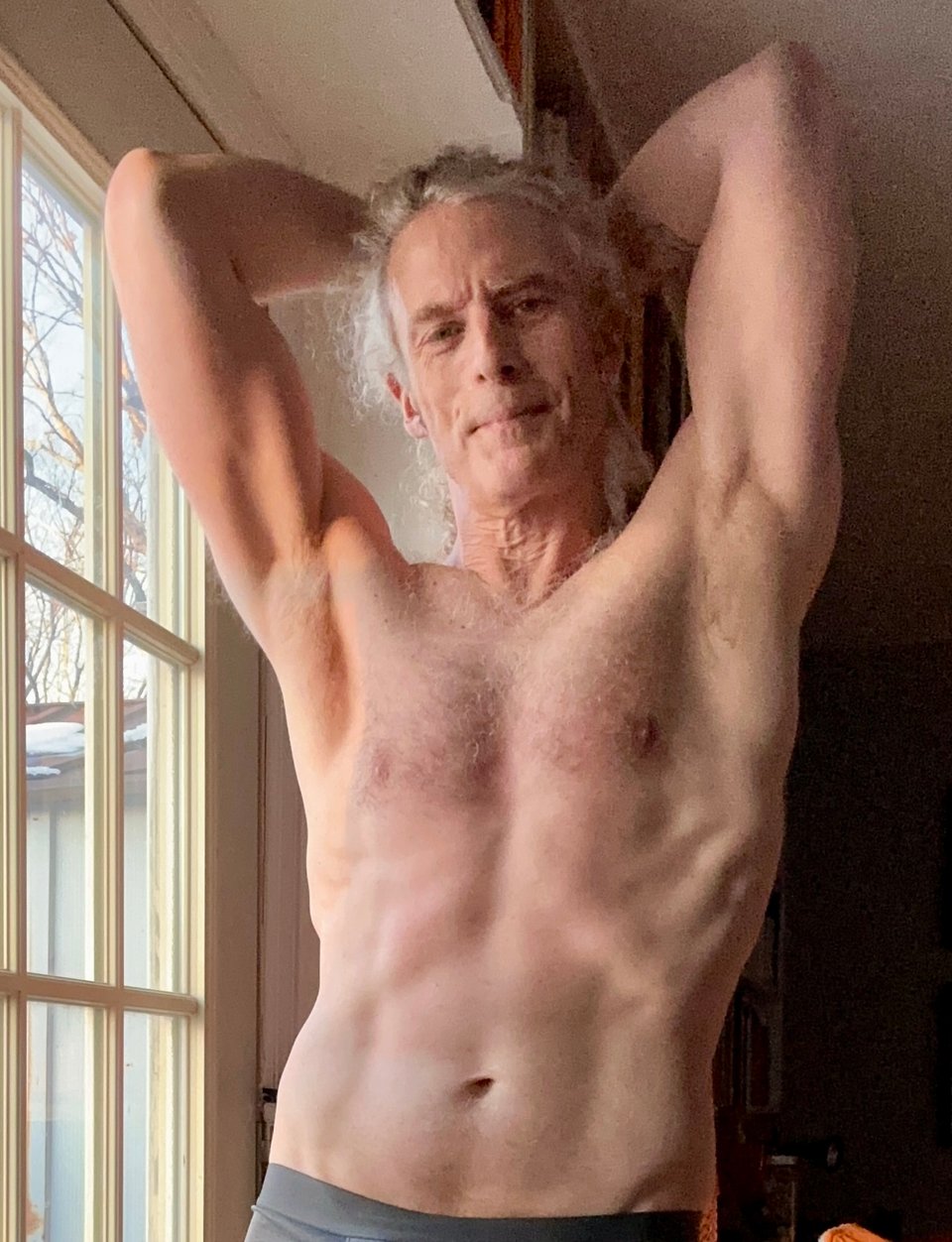 photo of shirtless white man in his mid-50s flexing his thorax, arms up and hands behind his head. He looks pretty good, but his wrinkly neck gives away the game