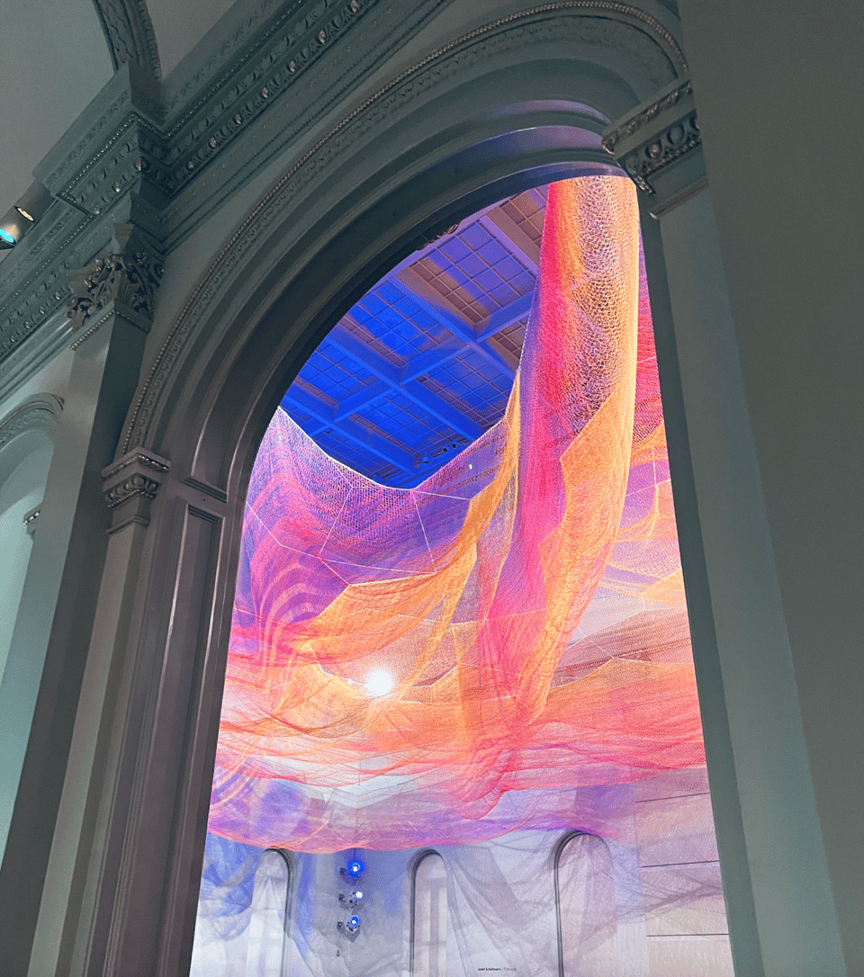 A photograph of multicolored netting suspended from the ceiling of the Renwick Gallery in Washington, D.C.