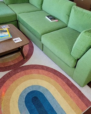 Partial shot of bright green sectional sofa and a rainbow-patterned area rug