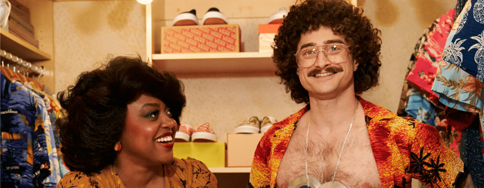Quinta Brunson (a Black woman with delightful cheeks) and Daniel Radcliffe (a white man with the world's bluest eyes) dressed as Oprah Winfrey and Weird Al Yankovic. This is a screencap from Weird.