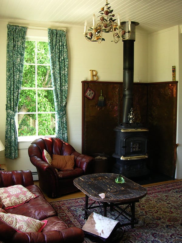 Living room scene - couch and comfy chair with a Persian Rug on the floor, willow coffee table and a fireplace in the corner.
