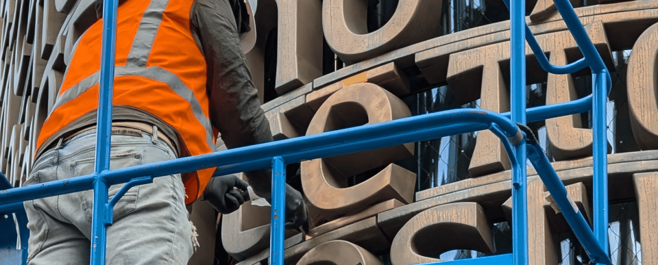 A letterworker on scaffolding about to commit a typo.