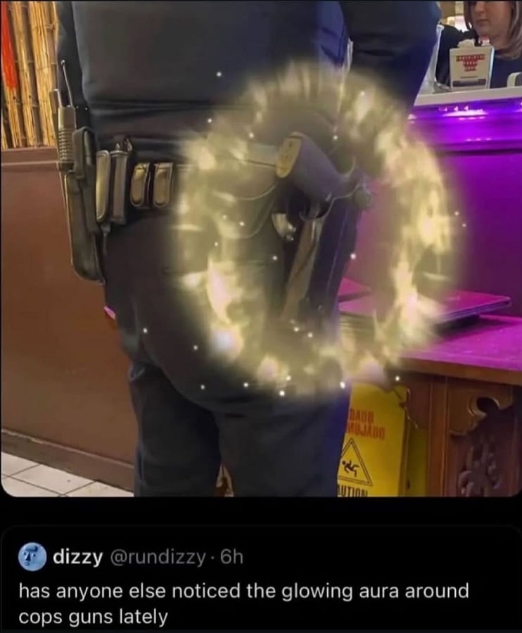 Photo of a cop standing at the counter at some sort of restaurant. There is a glowing gold aura around his service weapon. Below @rundizzy says: "has anyone else noticed the glowing aura around cops guns lately"