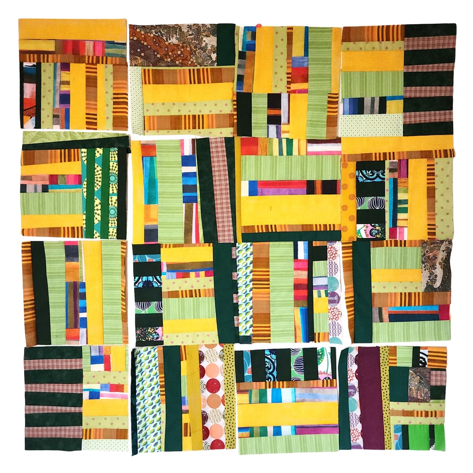 Photo of a patchwork quilt in progress, showing squares composed of primarily green and yellow fabrics.
