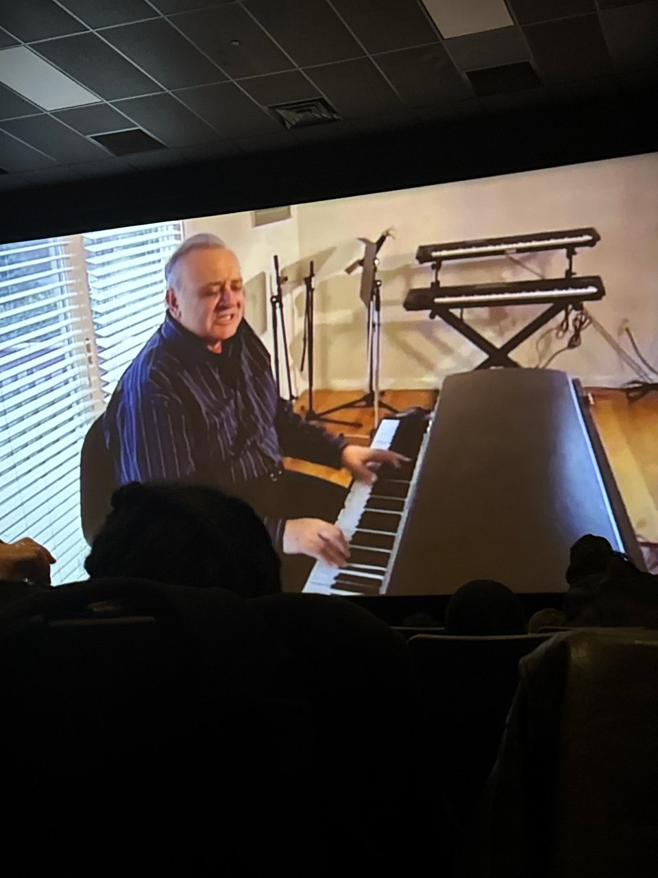 a photo of a pre-show at a movie theater. Angelo Badalamenti plays the piano as he discusses writing Laura Palmer's Theme with David Lynch.