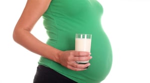 woman pregnant belly and milk in hand