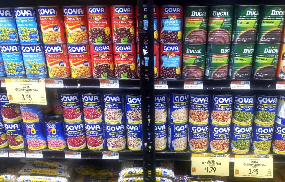 Photograph of Goya beans on two shelves at a grocery store. There are three sales tags for pigeon peas, with two being 3 cans for $5 and one being one bag of dried pigeon peas for $1.79.