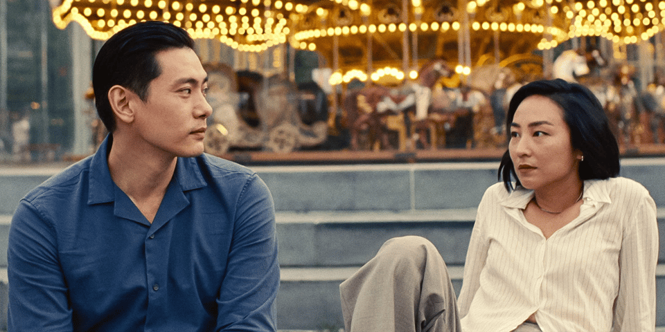 An example of a two shot from Past Lives, two characters sit in front of a carousel.