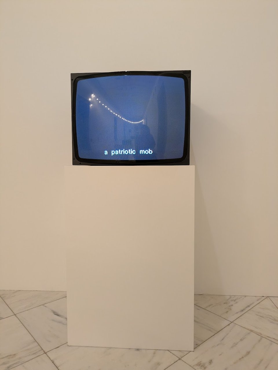 A television on a white pedestal. The video shows only the text