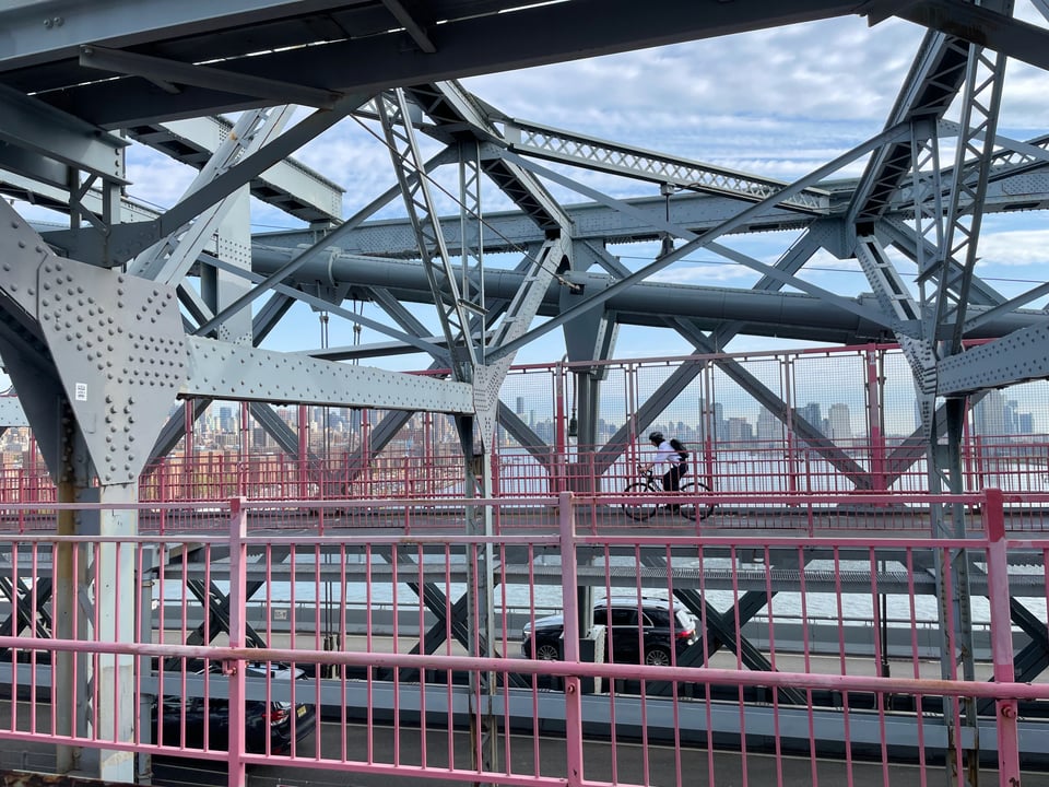 a person rides a bike across the Williamsburg Bridge