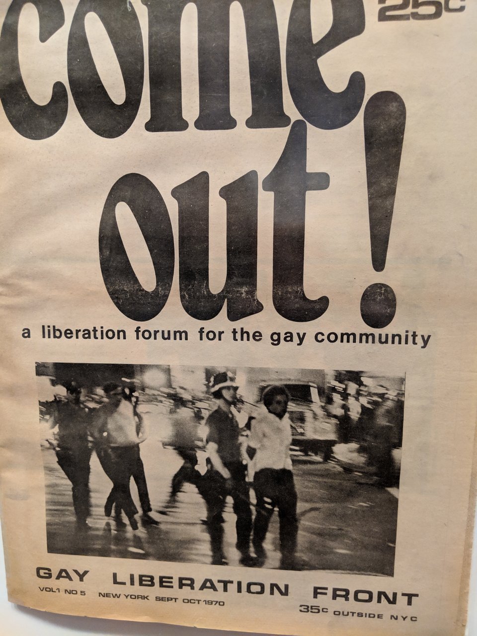 A newsletter from 1970 that says "COME OUT! a liberation forum for the gay community". There is a black and white image of cops arresting gay men.