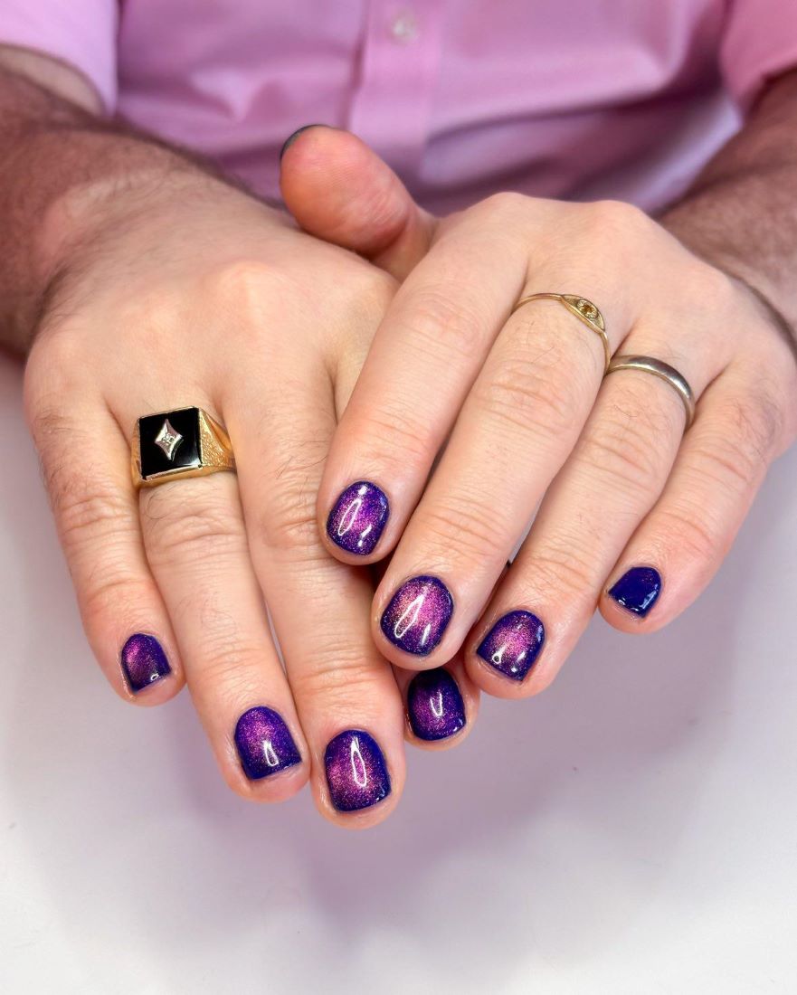 A dark blue manicure with pink cats eye