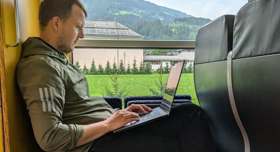 me sitting on a train in a mountain panorama, but working on my laptop