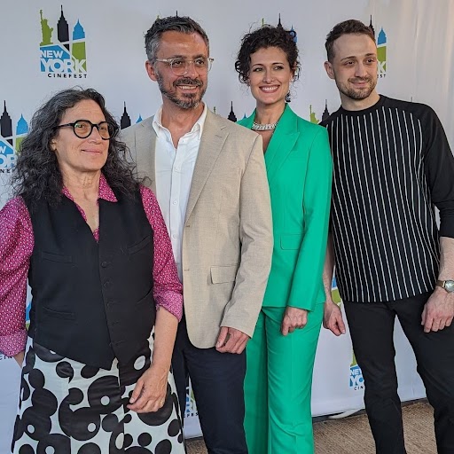 Pam, Rocco, Amy, and Andrew stand in dress clothes in front of the NY Cinefest banner.