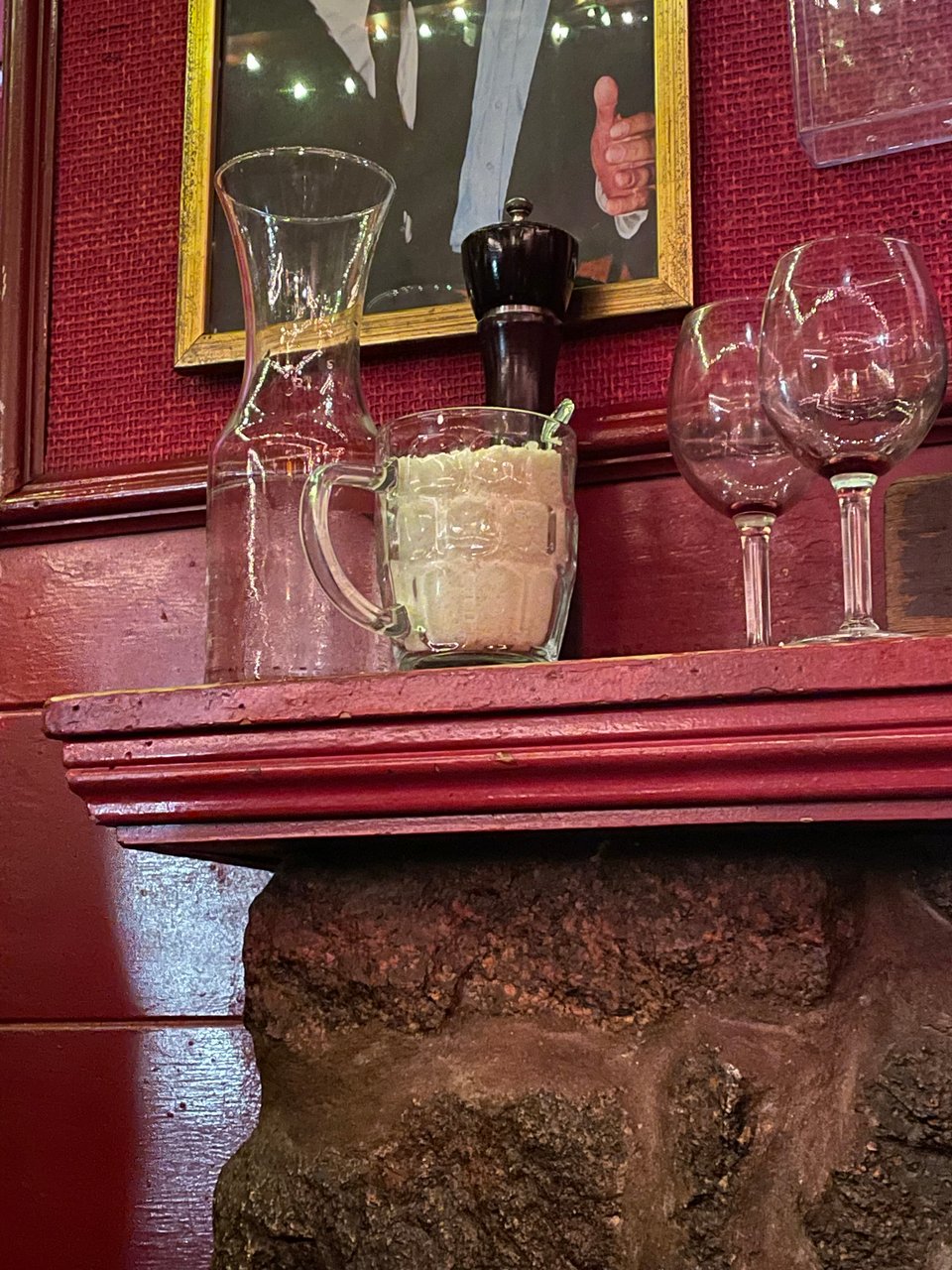 An Italian restaurant. A fireplace mantle with a mug of parmesan cheese on it