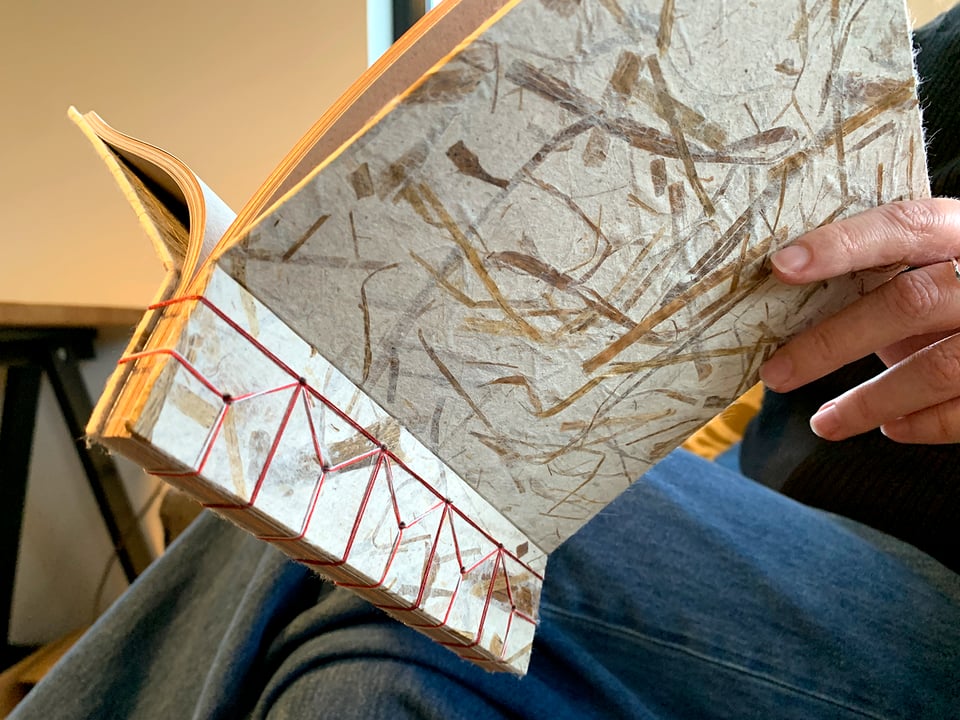 Paul holding his hand-bound book open on his lap.