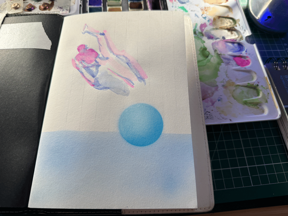 photo of my open sketchbook and on it is blue sphere i airbrushed hovering over a lighter blue airbruhed background. above it on the page is a figure drawing from the torso up of somone from behind reaching up and to the left. it was painted with blue and magenta watercolor. you can see some of myh palette in the background