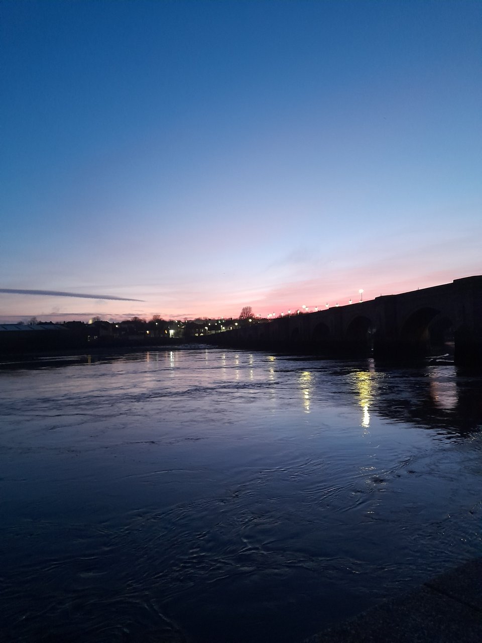 A sunset photo of the Old Bridge in Berwick-Upon-Tweed, and the river beneath it. There's an otter somewhere in the photo but it isn't really visible.