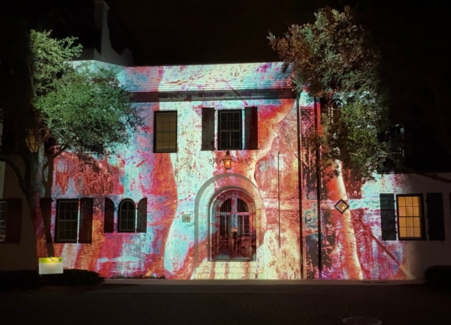 Night scene of a home with a colorful animation projected on it.