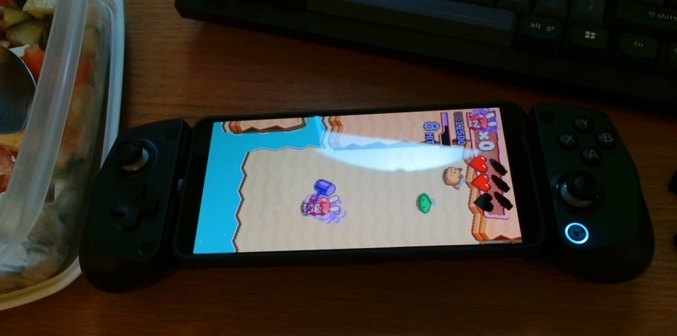 My Android phone with a backbone-style controller clamped to the sides of it, turning it into a device resembling a Nintendo Switch or Steam Deck. It is playing Hyper Bun Buster, although the view is rotated 90 degrees to the right.