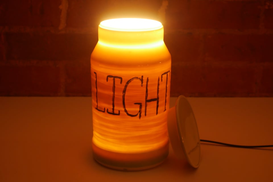 The same jar at night, with the light on and the lid off. The entire jar glows warm and orange, with a bight light from the top opening.