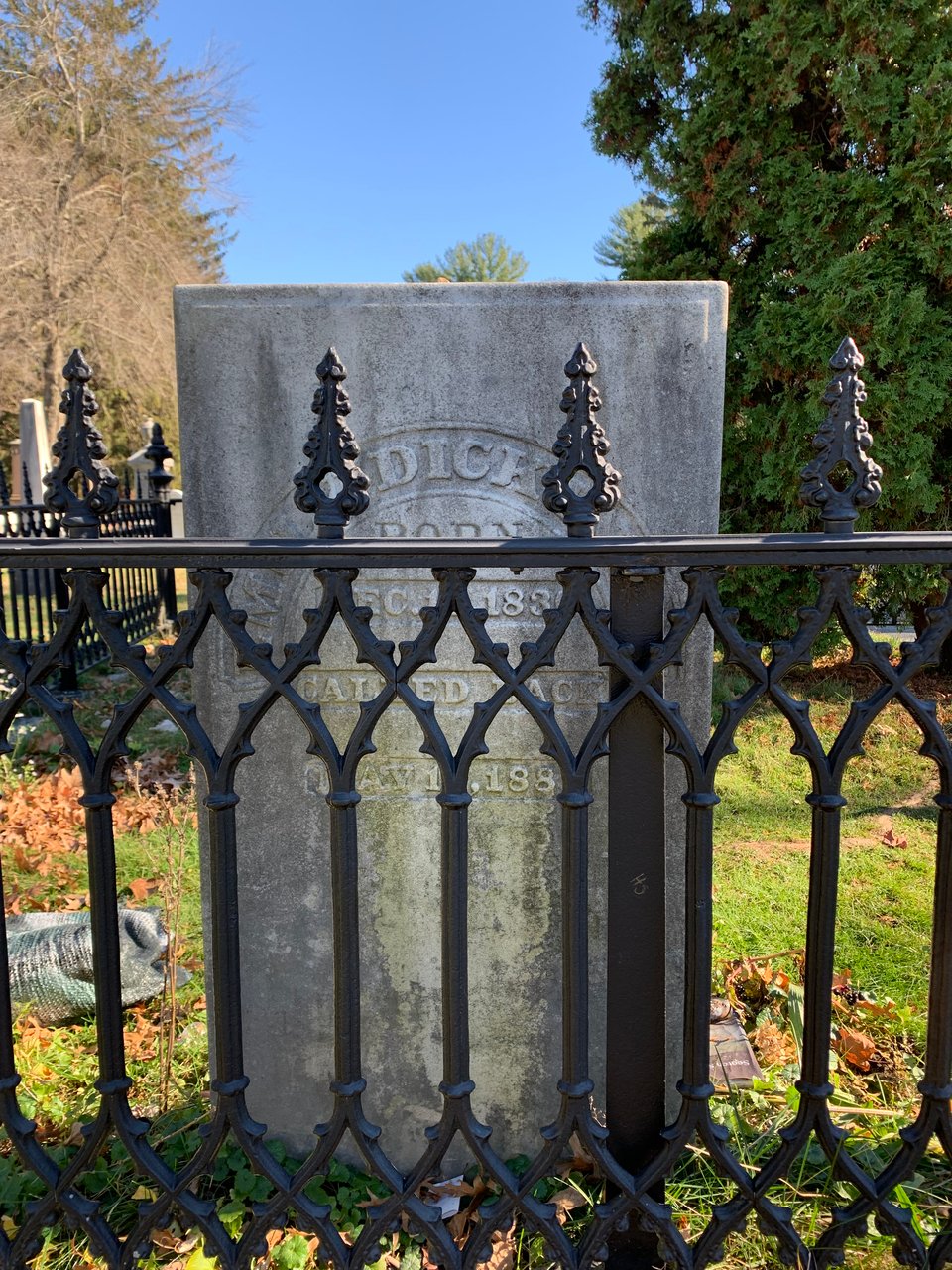 Photo of Emily Dickinson's gravestone, behind an iron fence