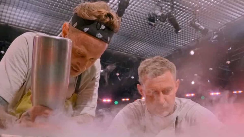 two men leaning over a counter covered in fog