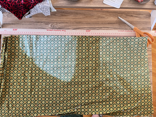 Section of green flower printed fabric with two large faded spots on it.