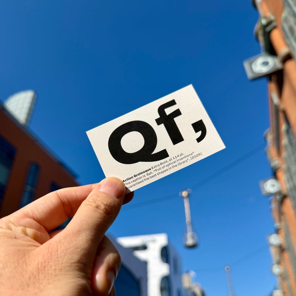 Hand holding a business card up to the very blue sky. The card has “Qf” in big letters which can only mean that the typedesigner is particularly proud of these particular letters. Because the letters themselves are void of meaning.