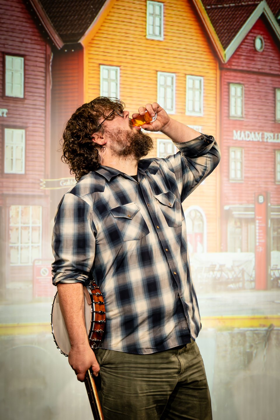 Zach holds a banjo in one hand and downs a bottle of pills in another