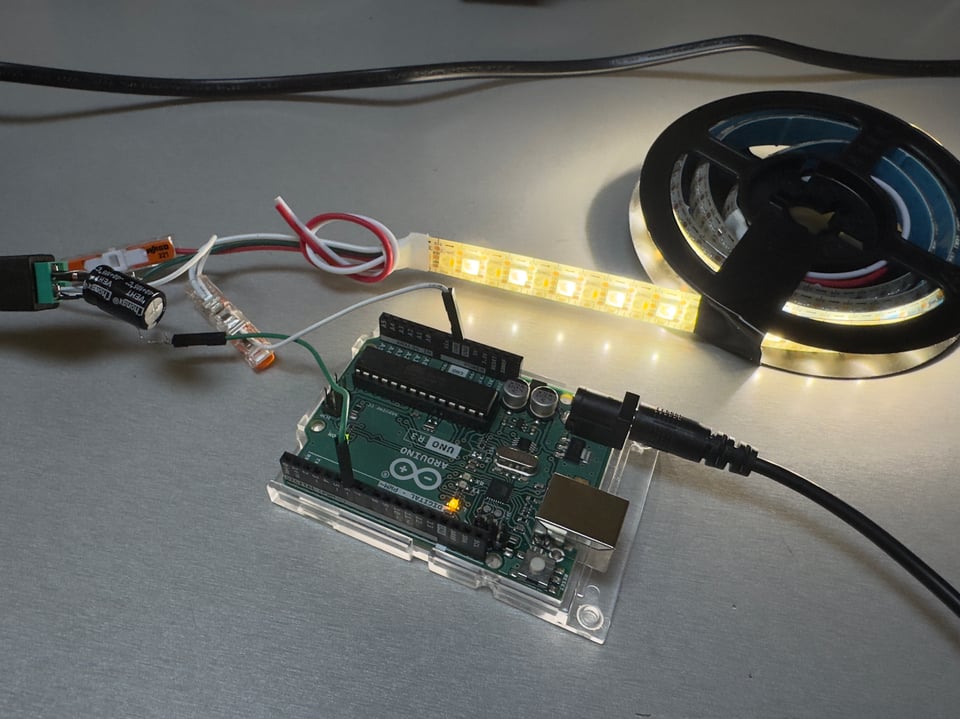 LED light strip with Arduino microcontroller and wiring on gray tabletop