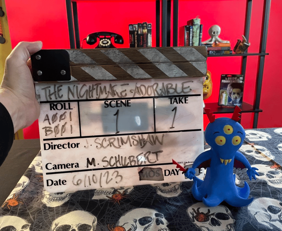 A clapboard reads The Nightmare Adorable. Next to a small toy of a cute little monster.
