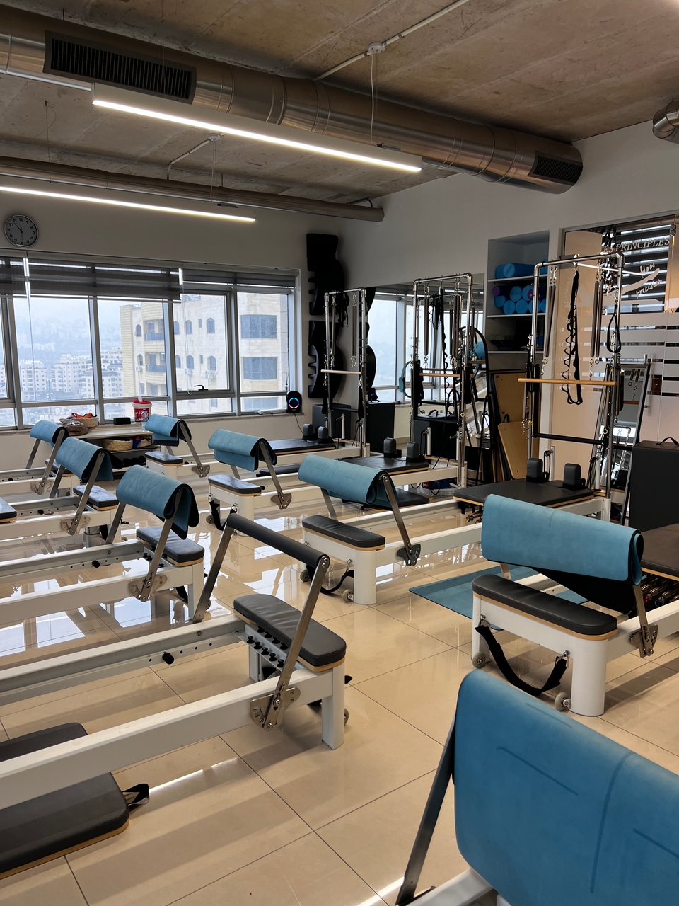 A room with a wall of windows filled with 10 Pilates reformers
