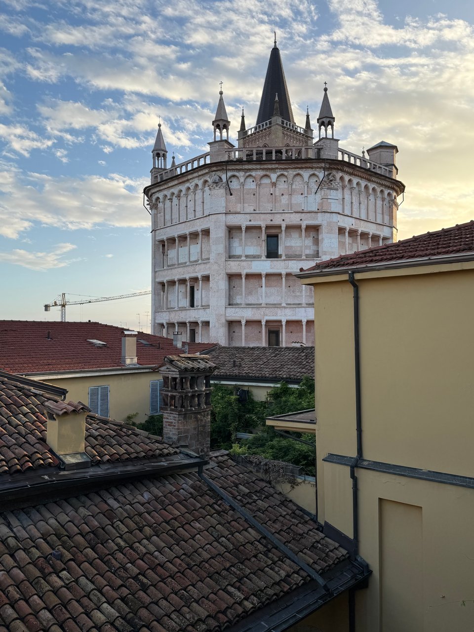 photo of view from palazzo of 800+-year-old baptistery tower in Parma, with sun rising off to right of frame