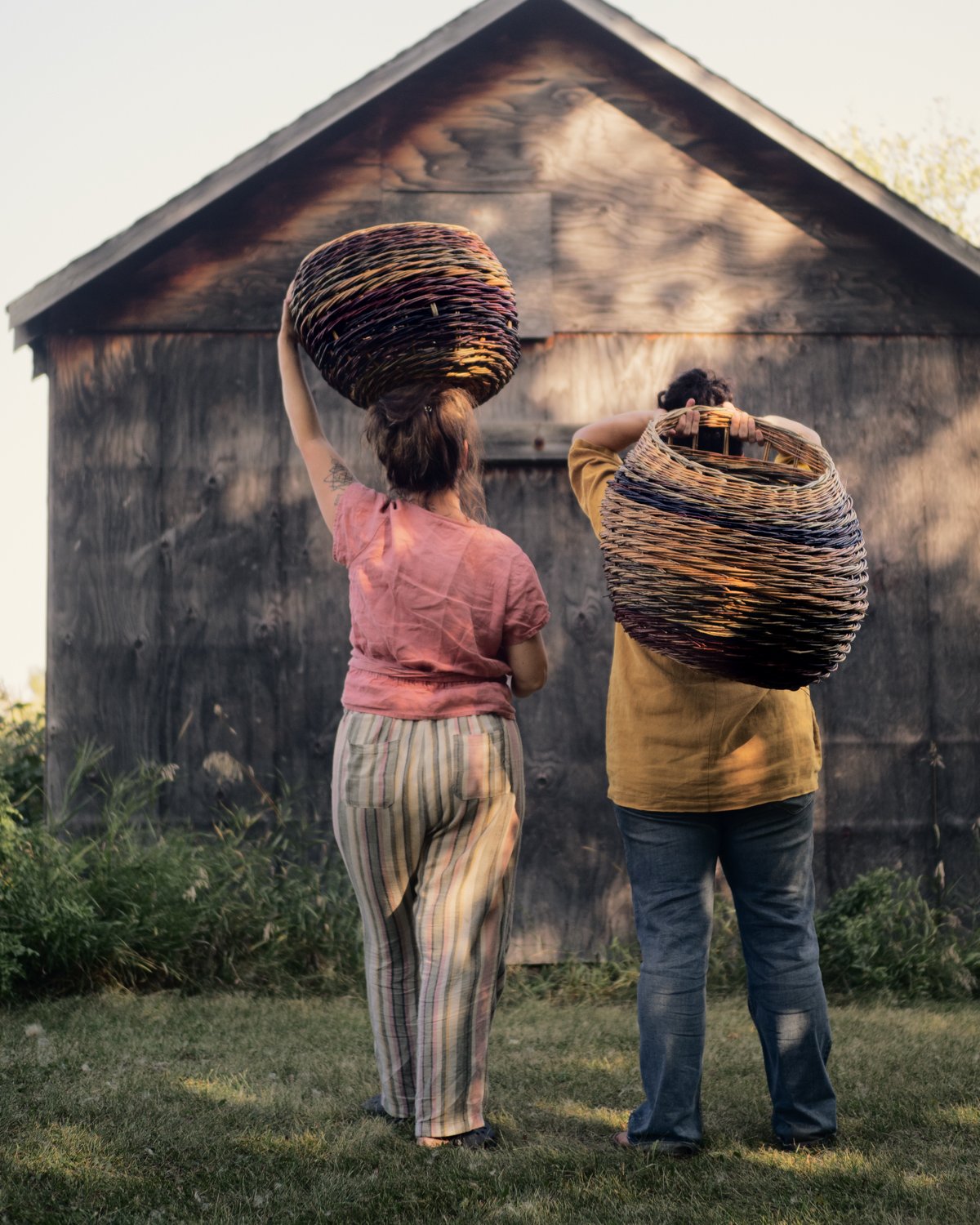 2 large twisted willow baskets held on the weavers back.