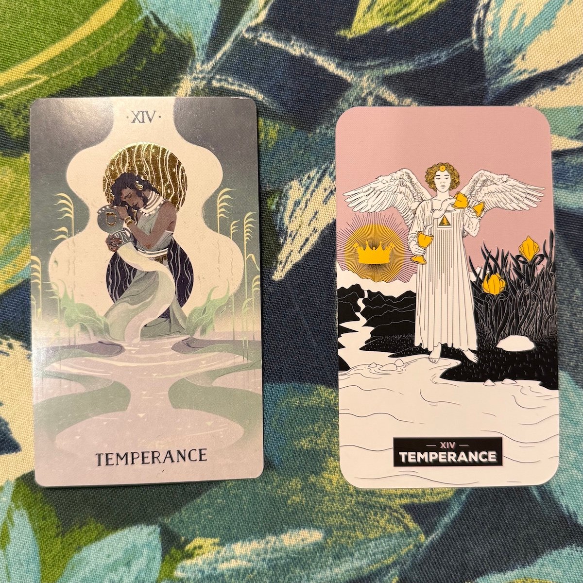 Two tarot cards, both labeled "Temperance", on a patterned teal and green surface; one card depicts a figure holding two vessels pouring liquid between them with a serene backdrop, and the other shows a winged figure holding two chalices and a river.
