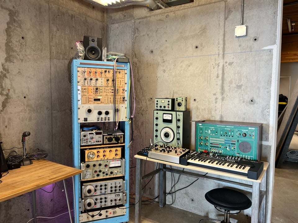 Baby blue test equipment rack containing a variety of gear with some additional retro-looking components to one side.