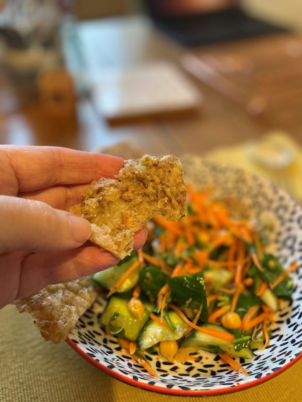 Wholegrain mustard spread on a pie of pearl barley pancake, with salad in the background.