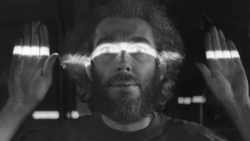 Filmmaker Hollis Frampton with a horizontal beam of light across his face.