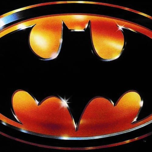 It's the Batman logo as used in the 1989 film, an oval with a bat shape inside it. The bat is black, everything around it is gold and there are glints on it, as if made of metal. The logo is zoomed in a bit so it's cut off on the left and right edges.