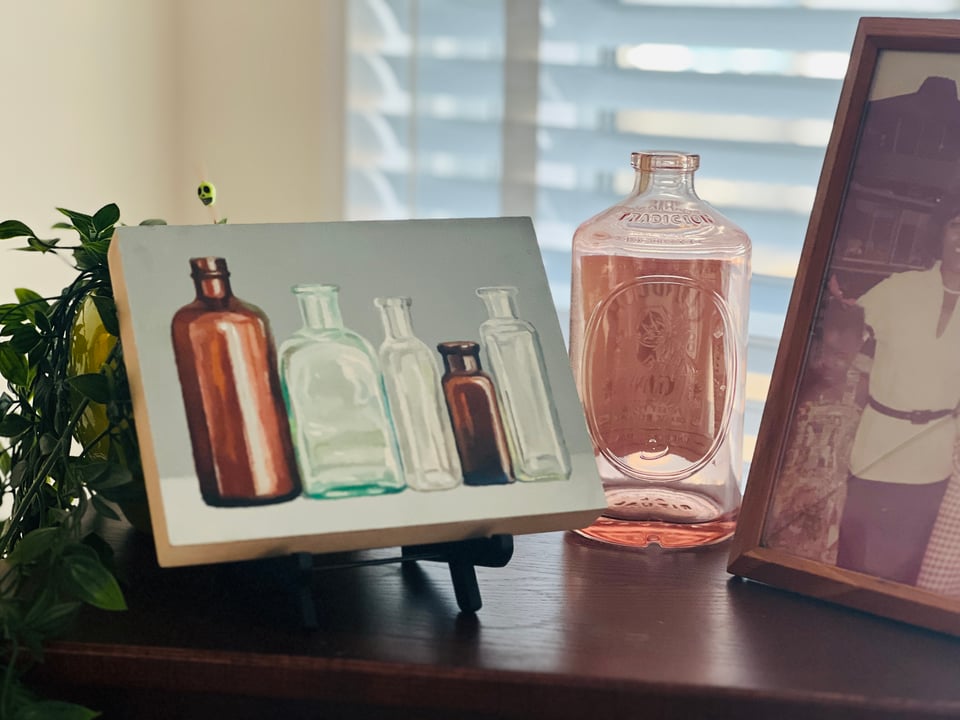 a painting of glass bottles alongside a family photo