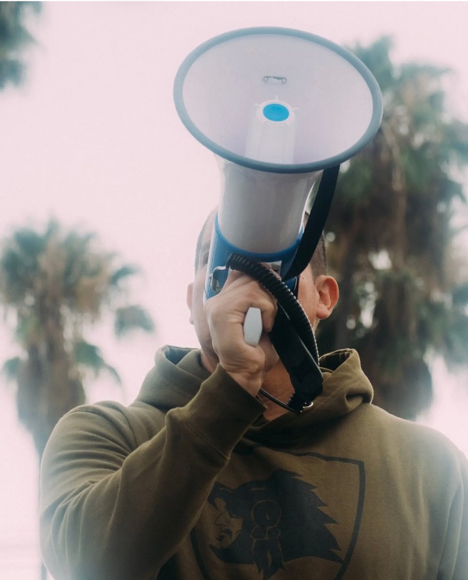 A man with megaphone warning about ICE’s presence