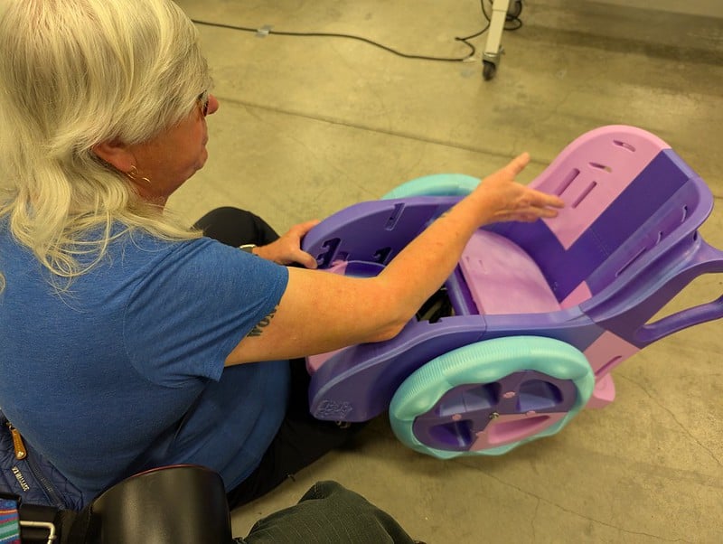 Emma examining a colorful 3d printed toddler wheelchair