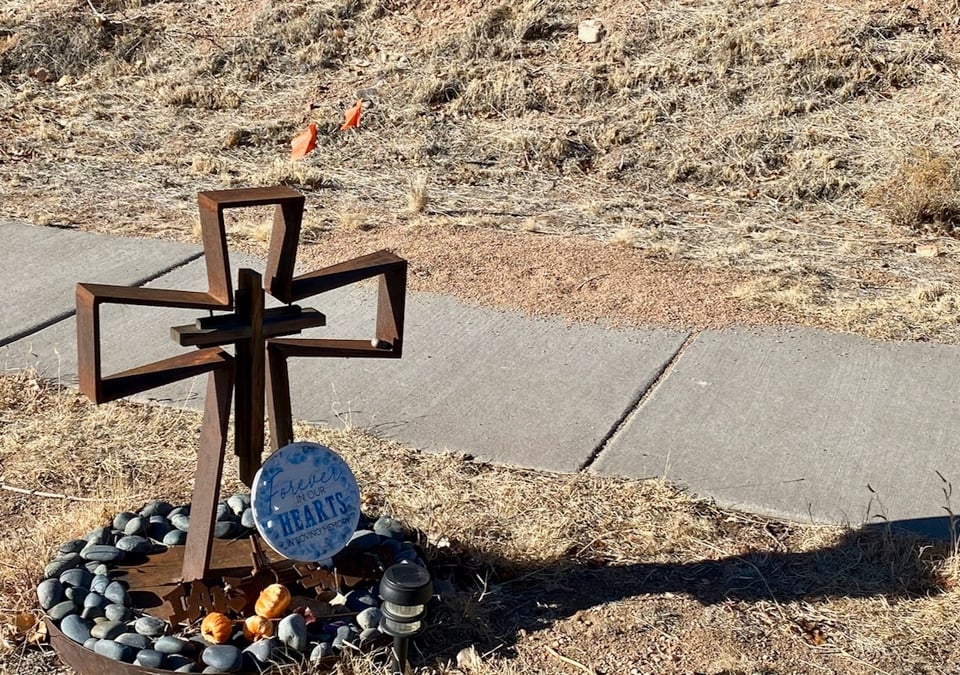 rusty iron cross surrounded by circle of rocks