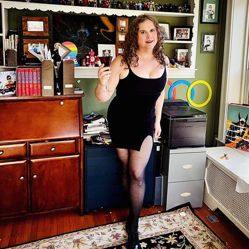 Jadzia, in a tight black dress, raising a toast.