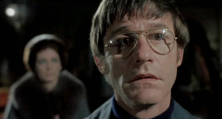 Roddy McDowall is opining in the garden with Ann in the background in The Legend of Hell House