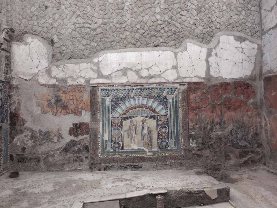 Herculaneum. A wall with broken plaster and frescoes. In the center is a mosaic of Neptune and Amphitrite.