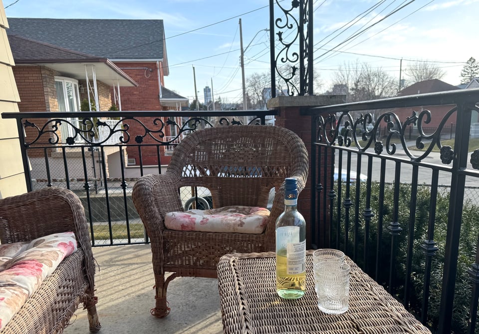 wicker porch furniture in the golden hour, and a table with wine and two classes