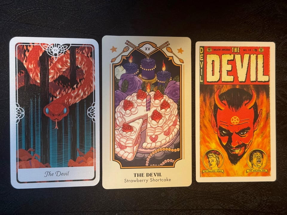 3 tarot cards in a row. Left most depicts a fiery snake in a forest, in the middle depicts a strawberry birthday cake with a slice pulled out of it, and right most is a fairly classic 1960s pulp style devil with a pentagram on his forehead