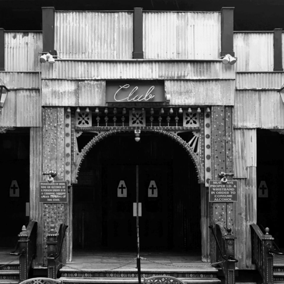 a church door under corrugated steel with a neon sign reading "club" above it